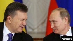 Președintele ucrainean de atunci, Viktor Ianukovici (stânga), îi face cu ochiul președintelui rus Vladimir Putin, la Kremlinul din Moscova, în decembrie 2013.