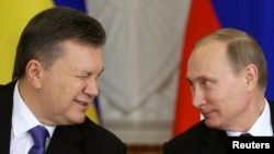Then-Ukrainian President Viktor Yanukovych (left) gives a wink to Russian President Vladimir Putin during a signing ceremony after a meeting of the Russian-Ukrainian Interstate Commission at the Kremlin on December 17, 2013.