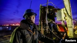 Нефтяники, занимающиеся техническим обслуживанием буровой установки в Кызылординской области Казахстана.