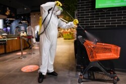 Një punëtor dezinfekton një shportë ushqimesh në një supermarket në Prishtinë. 17 prill, 2020.