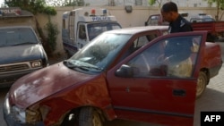 A Pakistani police officer inspects a vehicle in which an American woman was shot in Karachi on April 16.