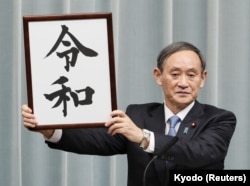 Генеральный секретарь правительства Японии Ёсихидэ Суга в прямом телеэфире показывает табличку с названием новой эры "Рэйва"