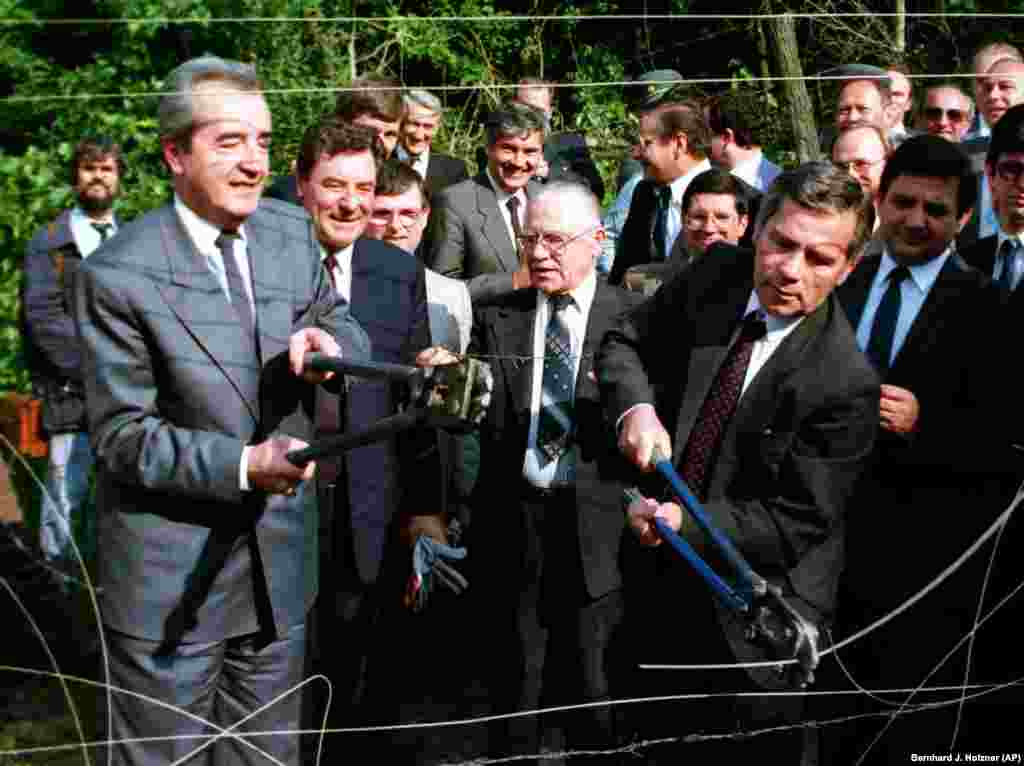 Hungarian Foreign Minister Gyula Horn (right) and his Austrian counterpart, Alois Mock, cut through the barbed wire marking the border in Sopron, Hungary, on June 27. The symbolic gesture was made to highlight Hungary&#39;s decision to begin dismantling its border surveillance.