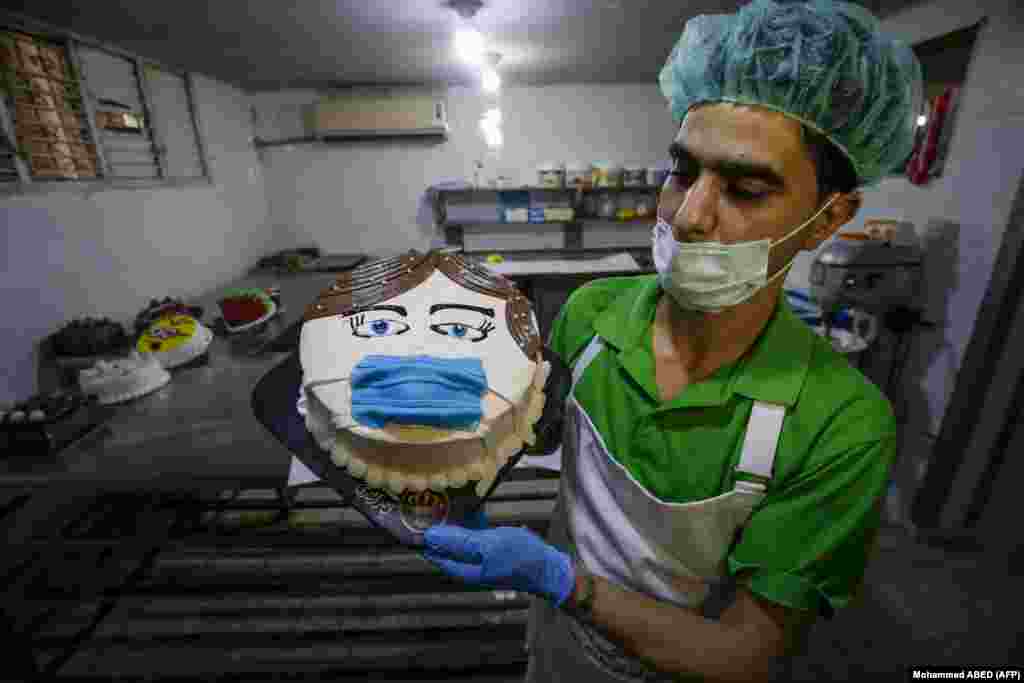 A Palestinian baker displays a cake that portrays a woman wearing a face mask at his shop in Khan Yunis in the southern Gaza Strip on March 30.&nbsp;