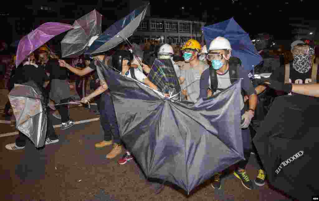 Pro-democracy protesters defend themselves with umbrellas against the police on Lung Wo Road, next to the Hong Kong Chief Executive's Office, part of the Central Government Office complex that the protesters are trying to surround. (epa/Alex Hofford)