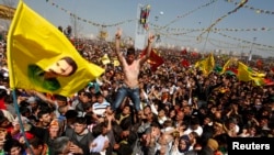 Demonstrators hold Kurdish flags and portraits of jailed Kurdistan Workers Party (PKK) leader Abdullah Ocalan during a gathering to celebrate Norouz in the southeastern Turkish city of Diyarbakir on March 21, 2013.