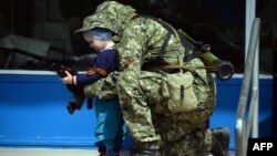 Иллюстрационное фото. Пророссийский боевик позирует для фотографии с ребенком. Донбас, апрель 2014 года