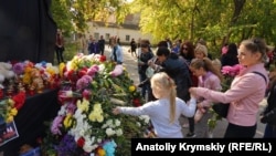 Люди возлагают цветы к монументу в память о погибших при нападении на колледж в Керчи, 18 октября 2018 года