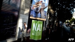 Люди проходять повз плакати з гаслами «так» (NAI) та «ні» (OXI) перед референдумом. Афіни, 3 липня 2015 року
