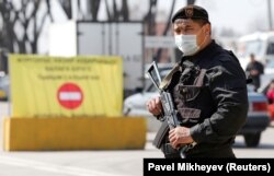 Карантинге жабылған Алматы қаласына кіреберіске қойылған бақылау бекетінде тұрған күш құрылымының қарулы қызметкері. 19 наурыз 2020 жыл.