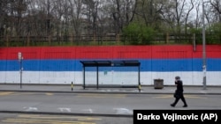 Autobuska stanica bez putnika i boje srpske zastave u pozadini. Zabeleženo u Beogradu 30. marta 2020