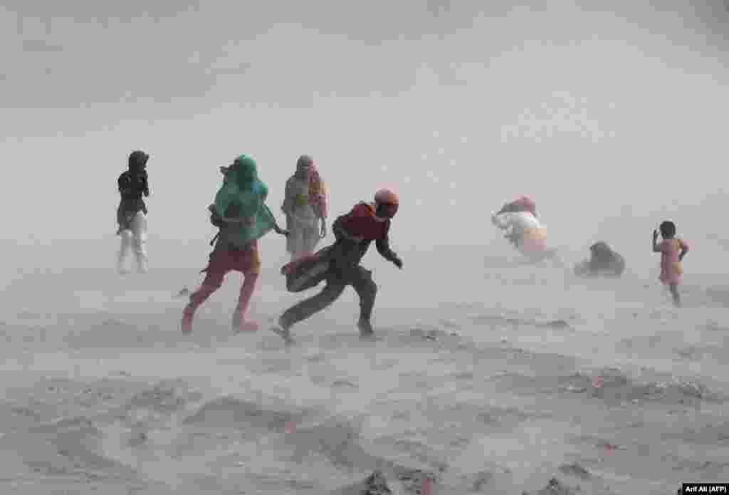 People walk through a windstorm near the Ravi River in Lahore, Pakistan, on September 15.