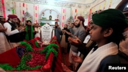 Men say a prayer over the grave of Mumtaz Qadri at the shrine built over his grave outside Islamabad on February 28.