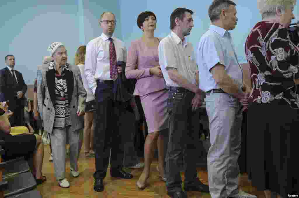 Ukrainian Prime Minister Arseniy Yatsenyuk (3rd left) queues to collect his ballot papers during voting in the presidential election at a polling station in Kyiv on May 25. (Reuters/Andrew Kravchenko)