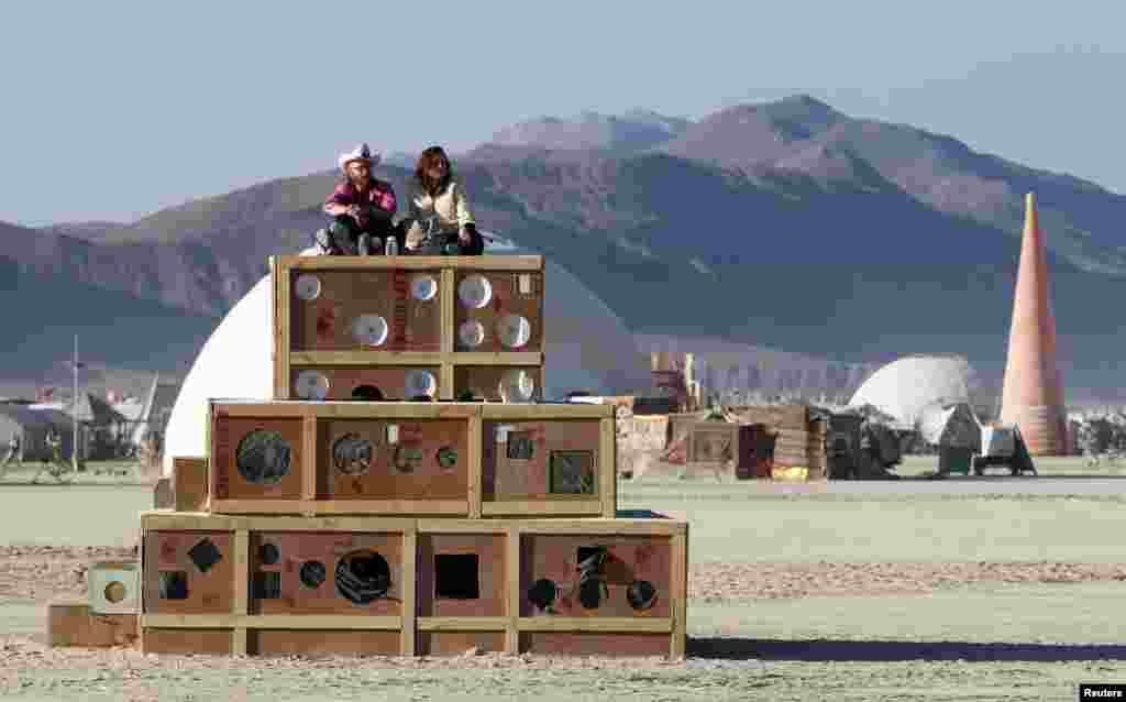 Festival-goers sit atop an art project to watch the sun rise.