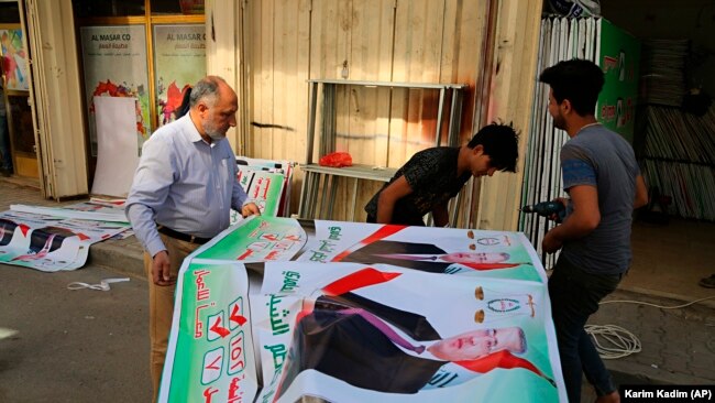 Iraqis prepare an election banner in Baghdad, March 18, 2018