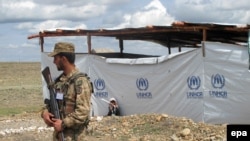 A Pakistani Army soldier stands guard as internally displaced persons from the South Waziristan tribal areas, where the Pakistani Army is engaged in a full-scale military operation, prepare to return.