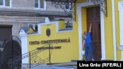 O angajată a Curții Constituționale de la Chișinău dezinfectează ușa de la intrare în contextul pandemiei de coronavirus, aprilie, 2020