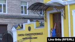 O angajată a Curții Constituționale de la Chișinău dezinfectează ușa de la intrare în contextul pandemiei de coronavirus