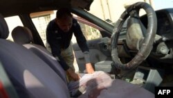 A Pakistani police officer inspects a vehicle in which a woman doctor was shot in Karachi on April 16. 