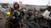 Защитник Украины возле уничтоженной российской военной техники в городе Буча неподалеку от Киева, 1 марта 2022 года