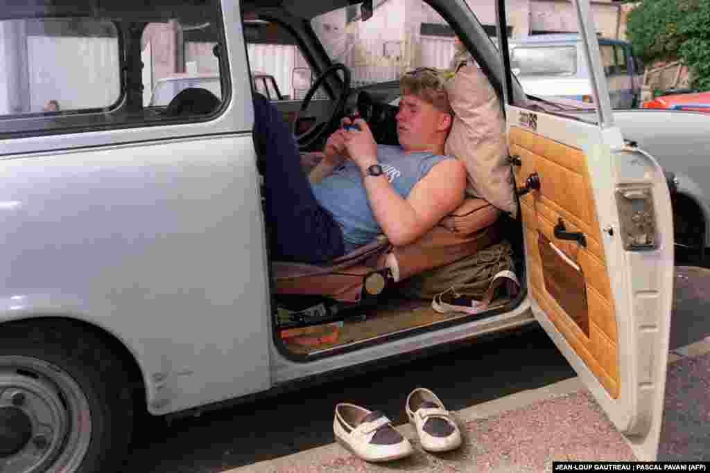 A refugee from East Germany camps out in his car in front of the West German consulate in Budapest on August 13. Throughout the summer, large numbers of East Germans traveled to Hungary with regular tourist visas and subsequently applied at the consulate for permission to enter West Germany.