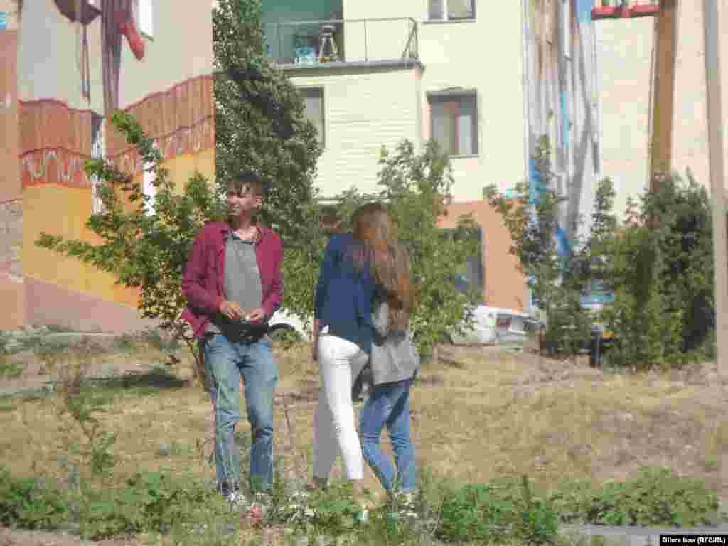 Граффитиді салып жатқан суретшімен əңгімелесіп тұрған жергілікті тұрғындар. Шымкент, 5 шілде 2016 жыл.