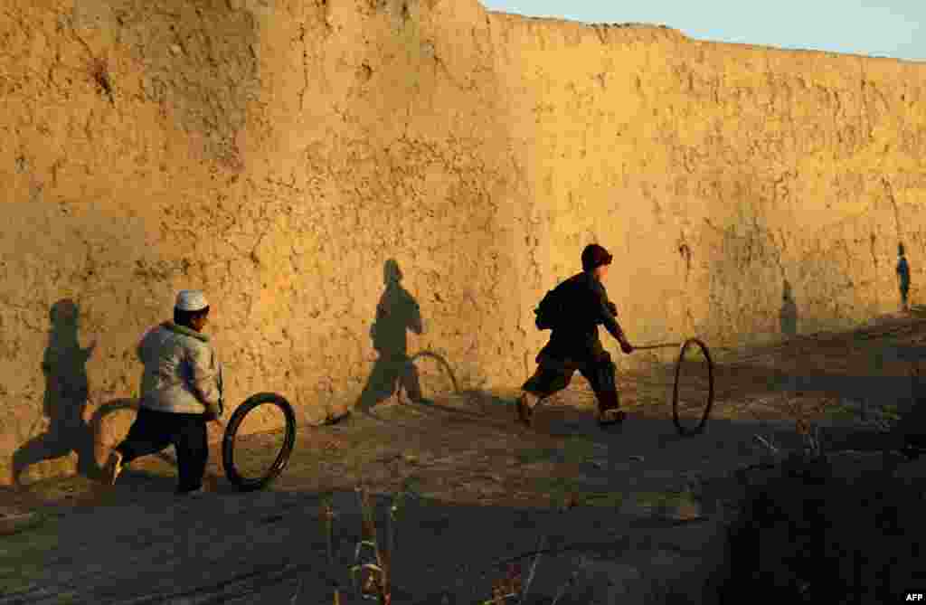 Afghan boys play with a tire outside their house in the Zhari district of Kandahar Province. (AFP/Javed Tanveer)