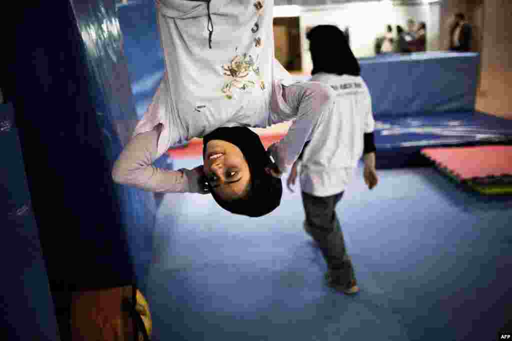 Mahsa Khakbazan hangs upside-down during a parkour training session at a sports hall in northern Tehran.