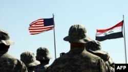 US troops stand to attention in front of American and Iraqi (R) flag. May 15, 2020