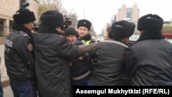 Полицейлер белсенді Дулат Ағаділді (ортада) күштеп ұстап жатқан сәт. Нұр-Сұлтан, 26 қазан 2019 жыл.