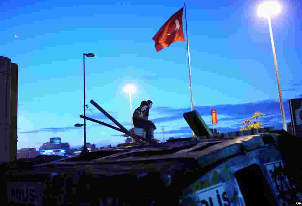 Turkish youths wearing "V for Vendetta" masks stand on top of a public bus on Istanbul's Taksim Square on the night of June 7-8. For more than a week now, antigovernment demonstrations have been taking place in Istanbul and other Turkish cities, leaving three dead and hundreds injured. (AFP/Bulent Kilic)