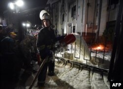 A fireman extinguishes the flames from a Molotov cocktail thrown into the embassy complex.