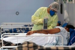 Родственник посещает пациента в импровизированной больнице, организованной в спортзале в Сан-Паулу