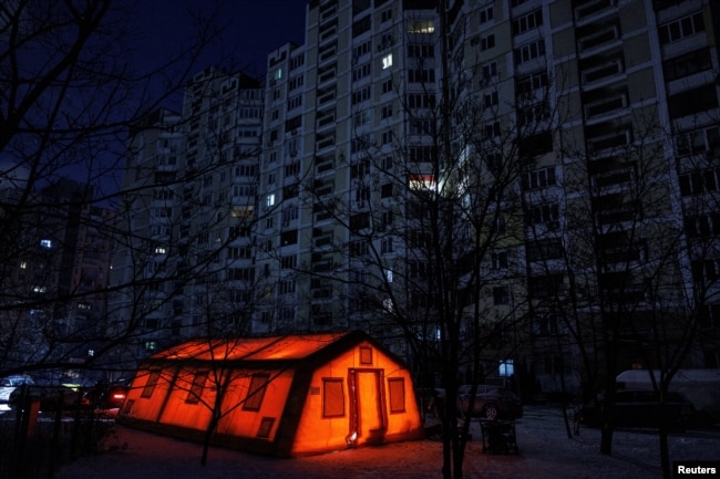 Намет державного пункту гуманітарної допомоги перед багатоквартирним будинком під час відключення електроенергії, Київ, Україна, 12 січня 2026 року