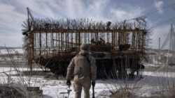 Український військовий в Донецькій області біля танка із протидроновим захистом