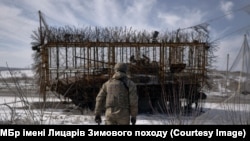 Український військовий в Донецькій області біля танка із протидроновим захистом