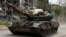 UKRAINE – Service members of pro-Russian troops drive a tank along a street past a destroyed residential building during Ukraine-Russia conflict in the town of Popasna in the Luhansk Region, May 26, 2022