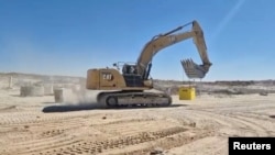 Un vehicul militar israelian mută elemente de barieră pentru a marca „linia galbenă” de armistițiu din Gaza.