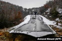 A man walks past a collapsed road due to heavy floods in the Kosovar village of Sferke on January 10.