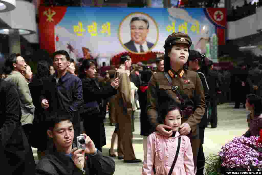 A soldier and her child attend a flower exhibition, part of celebrations marking the 105th anniversary of the birth of the late supreme leader Kim Il-sung in Pyongyang, North Korea, April 16, 2017. (EPA-EFE/How Hwee Young)