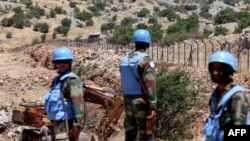 Soldiers from the United Nations Interim Forces in Lebanon (UNIFIL) stand along the barbed-wire fence marking the border with Israel. 