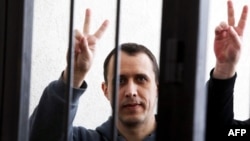 Belarusian opposition figure Paval Sevyarynets flashes the victory sign from the defendant's cage at a courthouse in the town of Mahilyou on May 25. 