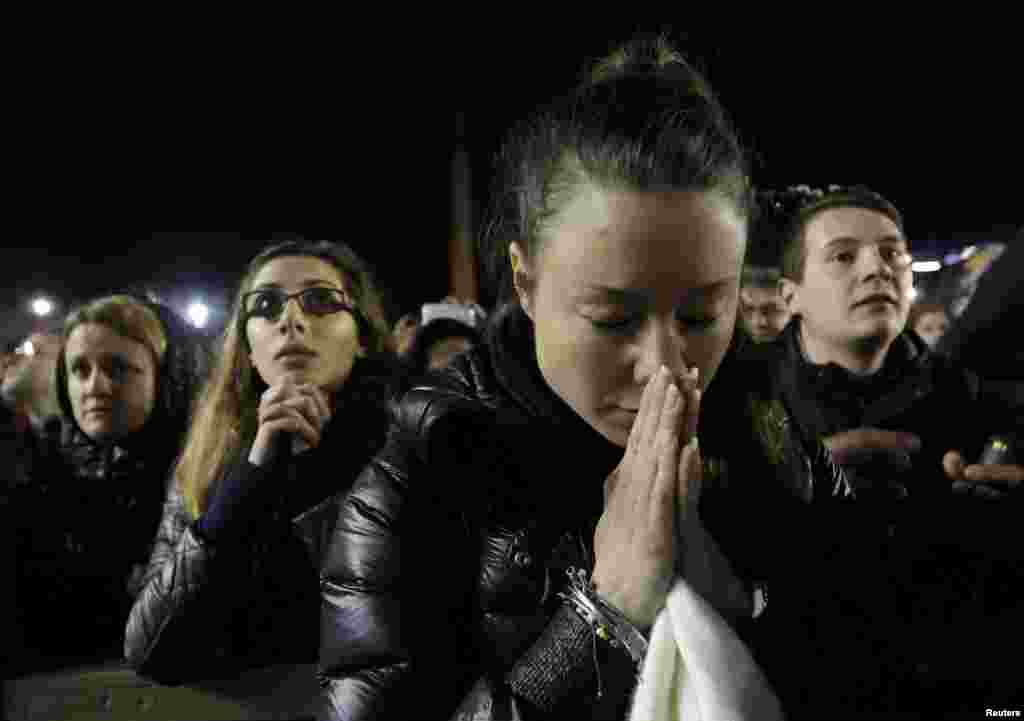 People pray for newly elected Pope Francis as he appears on the balcony of St. Peter&#39;s Basilica.