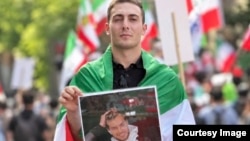علی زارعی عکس حمیدرضا روحی از دیگر قربانیان خشونت‌های حکومت در قبال معترضان را در یکی از گردهمایی‌های مخالفان حکومت در خارج از کشور در دست دارد