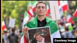 علی زارعی عکس حمیدرضا روحی از دیگر قربانیان خشونت‌های حکومت در قبال معترضان را در یکی از گردهمایی‌های مخالفان حکومت در خارج از کشور در دست دارد