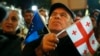 A demonstrator holds an EU and a Georgian national flag as he attends an opposition protest against the results of the parliamentary elections in Tbilisi on October 28.