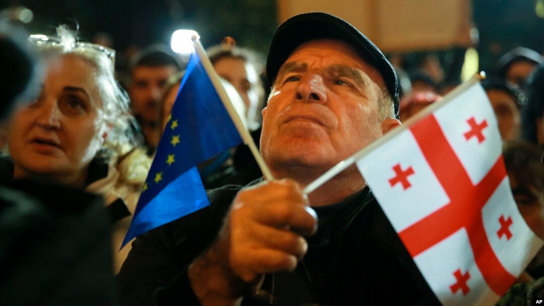 A demonstrator holds an EU and a Georgian national flag as he attends an opposition protest against the results of the parliamentary elections in Tbilisi on October 28.
