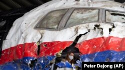 судии и адвокати ги гледаат остатоците од летот MH17 на Малезија ерлајнс, во воената воздухопловна база Гилзе-Ријен, 26 мај 2021 година