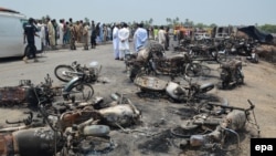 Pakistan -- People gather behind burnt motorcycles and vehicles at the scene of an Oil tanker accident on the outskirts of Bahawalpur, June 25, 2017